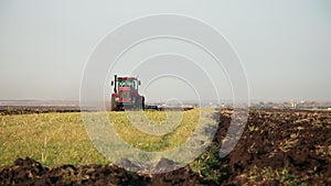 Red modern tractor with reverse plow plows the field. Agricultural work in the field, agribusiness.