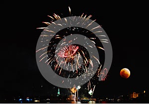 Red moon and fireworks near river in night