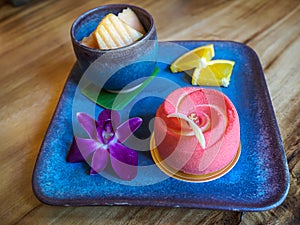 Red moose cake with orchid and fruits in Thai style decoration on dishes and on wood table