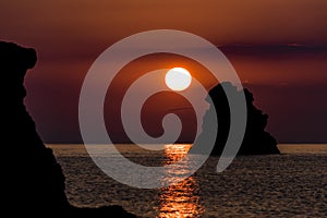 Warm sunrise over sea rocks in Taormina, Sicily