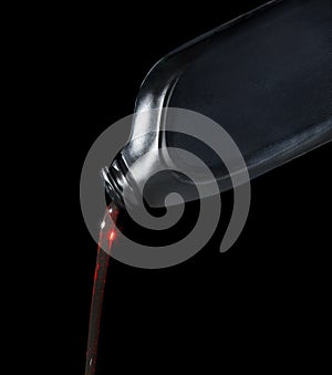 Red motor oil lube pouring from black plastic bottle