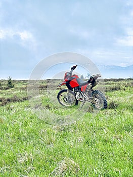 A red motorbike standing a top of a mountain, showcasing the thrilling adventure and triumph of conquering the rugged