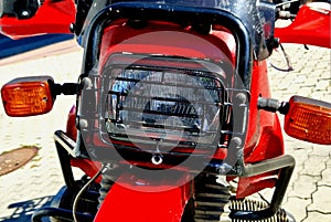 red motorcycle with a cross-country fender and a grille protecting the