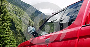 Red mountain car with the mirror on a mountain background traveling