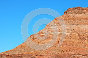 A red mountainside against a blue sky.