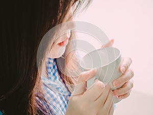 red mouth of asian girl in blue flannel shirt hold hot coffee for drink in morning time with soft focus foreground and background