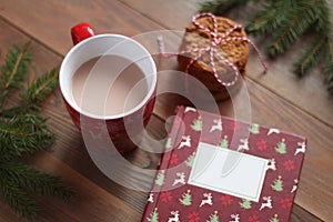 Red mug of cocoa, Christmas book and pile of cookies on the wooden table