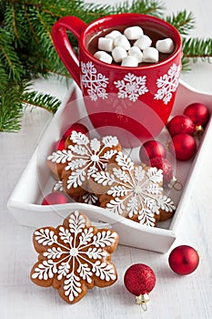 Red mugs with hot chocolate and marshmallows and gingerbread cookies