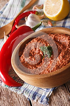Red Muhammara snack in wooden bowl closeup. vertical
