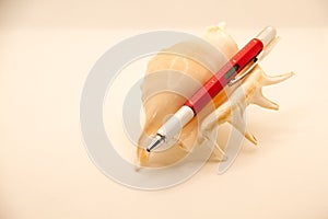Red multitool pen on sea shell in white background