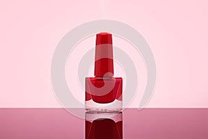 Red nail polish bottle on pastel pink background