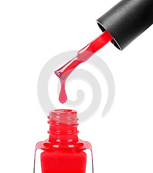 Red nail polish dripping from brush into bottle closeup