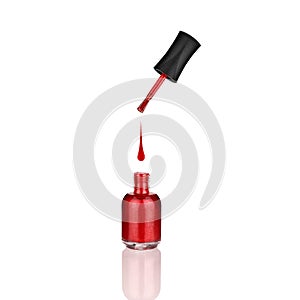 Red nail polish glass bottle, brush & drop on white background isolated close up with mirror reflection, opened varnish package