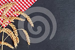 Red napkin tablecloth and wheat on blsck stone background