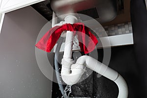 Red Napkin Tied Under The Leakage Sink Pipe