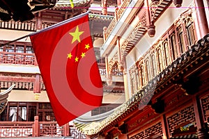 Red national flag of China against old chinese buildings at Yuyuan Garden in Shanghai, China