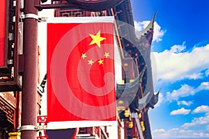 Red national flag of China against old chinese buildings at Yuyuan Garden in Shanghai, China