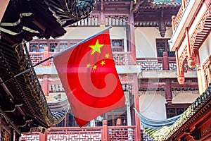 Red national flag of China against old chinese buildings at Yuyuan Garden in Shanghai, China