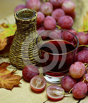 Red natural wine homemade wicker bottle and grapes