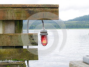 Red navigation light hanging from railing on wharf showing entry direction