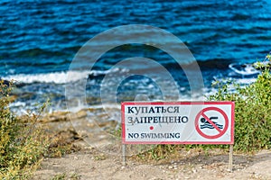 Red no swimming sign posted on beach