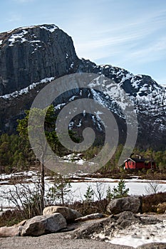 Red norwegian wooden house in the winter forest close to the mountains