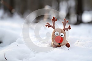 a red-nose reindeer toy on a snowy surface