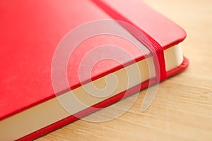 Red notebook close-up on the wooden table. Stylish sketchbook for painting, drawing and writing.