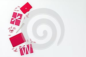 Red notebook, gift box, pen and clips on white background. Flat lay