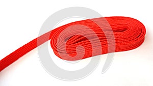 Red nylon rope on white background. Fabric rope in red color folded in a coil