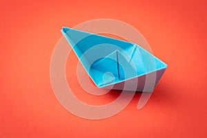 Red ocean business competition, survive success or winner company metaphor concept, blue origami paper ship on red background as