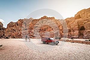 Red off-road car and two camels in Petra city