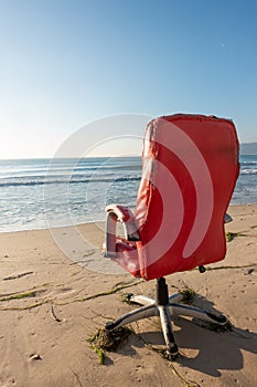 Red office chair on beach