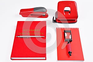 Red office supplies: stapler, hole punch, Notepad, magnifier, book and pen