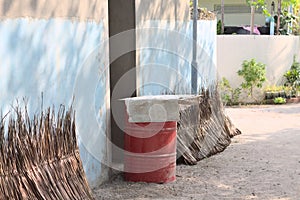 Red oil tank in front of the door and stacked dried palm leaves