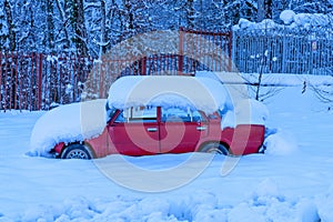A red old car under snow
