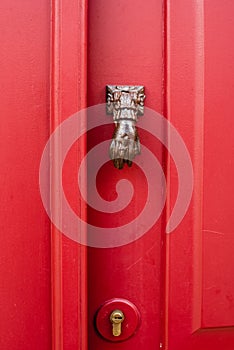 Red old door with doorknocker Metal arm of woman or man