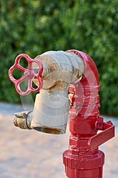 Red old fireplug with white valve against of a wall background