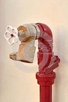 Red old fireplug with white valve against of a wall background