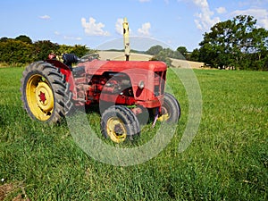 Red old tractor standing in a green field