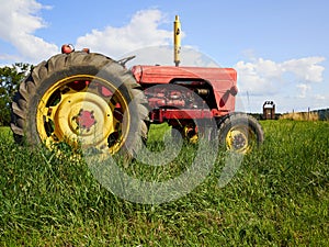 Red old tractor standing in a green field