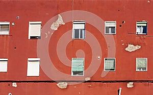 Red old wall of a house with many windows