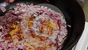 Red onion and curry are fried in a pan. Cooking jollof rice