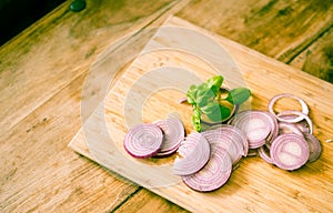 Red onion slices isolated on wooden chopping board