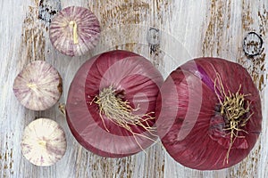 Red onions and garlic on the white painted wooden background.