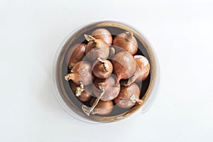 Red onions in wooden bolw on white wooden planks background