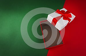 Red open gift box with ribbon on green and red Christmas background