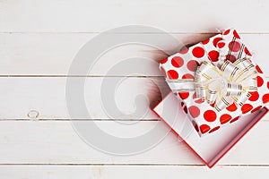Red open gift box with ribbon on white background on white wooden background with copy space, top view.