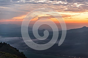 Red, oragne and blue dynamic sunrise with fog laying in valley