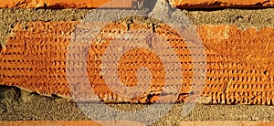 Red - orange brick close-up. Damaged surface exposed to weathering and destruction